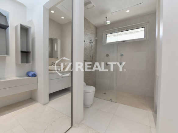 Spacious bathroom in Coral Shell Penthouse B featuring a rainfall shower, sleek vanity, and modern design elements.