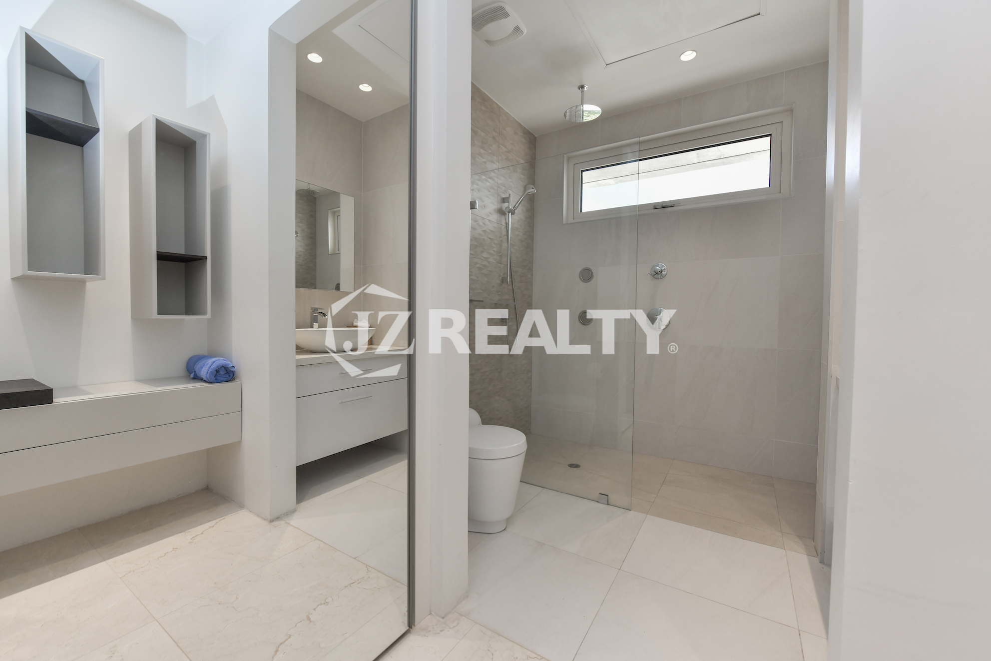 Spacious bathroom in Coral Shell Penthouse B featuring a rainfall shower, sleek vanity, and modern design elements.