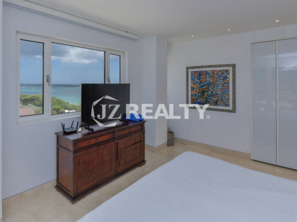 Bright and airy master bedroom in Coral Shell Penthouse B featuring a king-sized bed, large windows, and spectacular ocean views.
