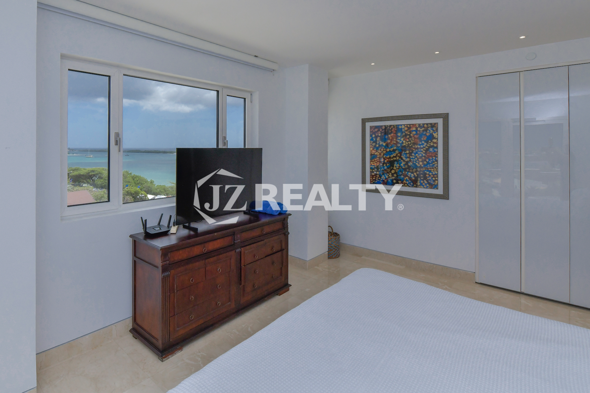 Bright and airy master bedroom in Coral Shell Penthouse B featuring a king-sized bed, large windows, and spectacular ocean views.