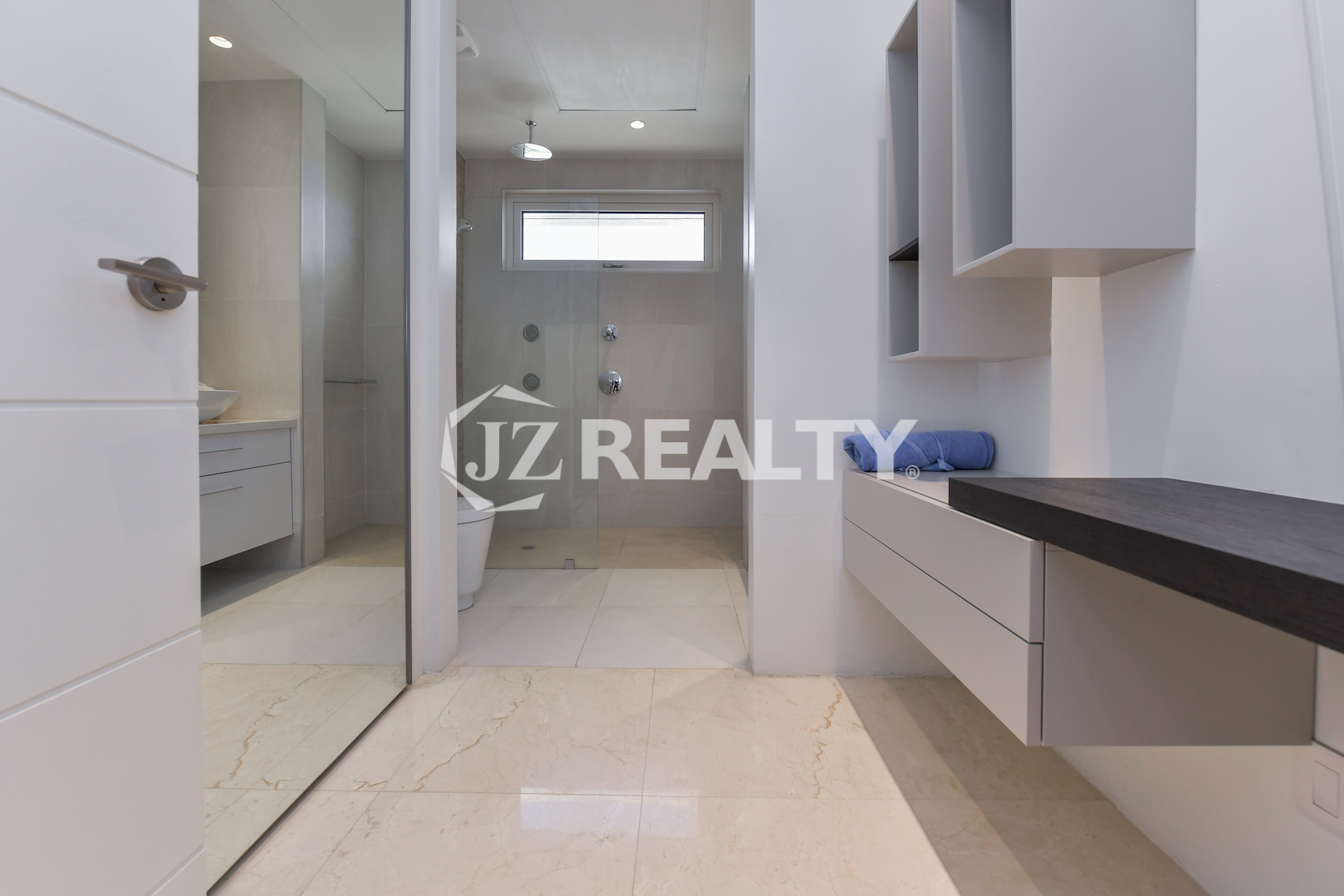 Stylish dressing area in Coral Shell Penthouse B featuring sleek built-in storage, a vanity counter, and marble flooring.