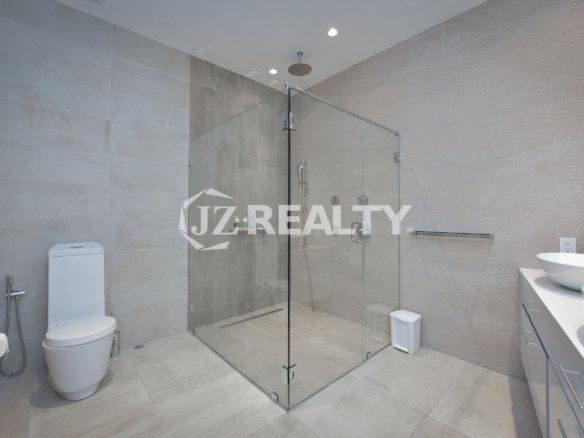 Spacious ensuite bathroom in Coral Shell Penthouse B featuring a glass-enclosed rainfall shower, sleek vanity, and high-end fixtures.