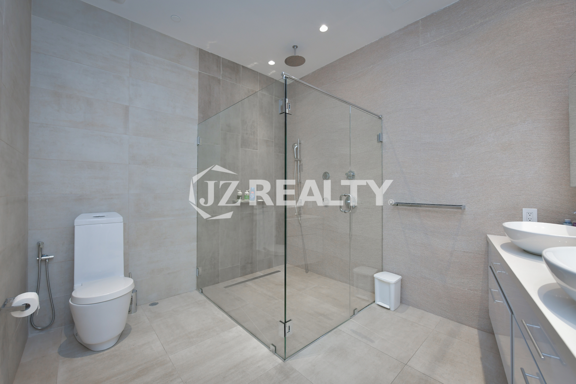 Spacious ensuite bathroom in Coral Shell Penthouse B featuring a glass-enclosed rainfall shower, sleek vanity, and high-end fixtures.
