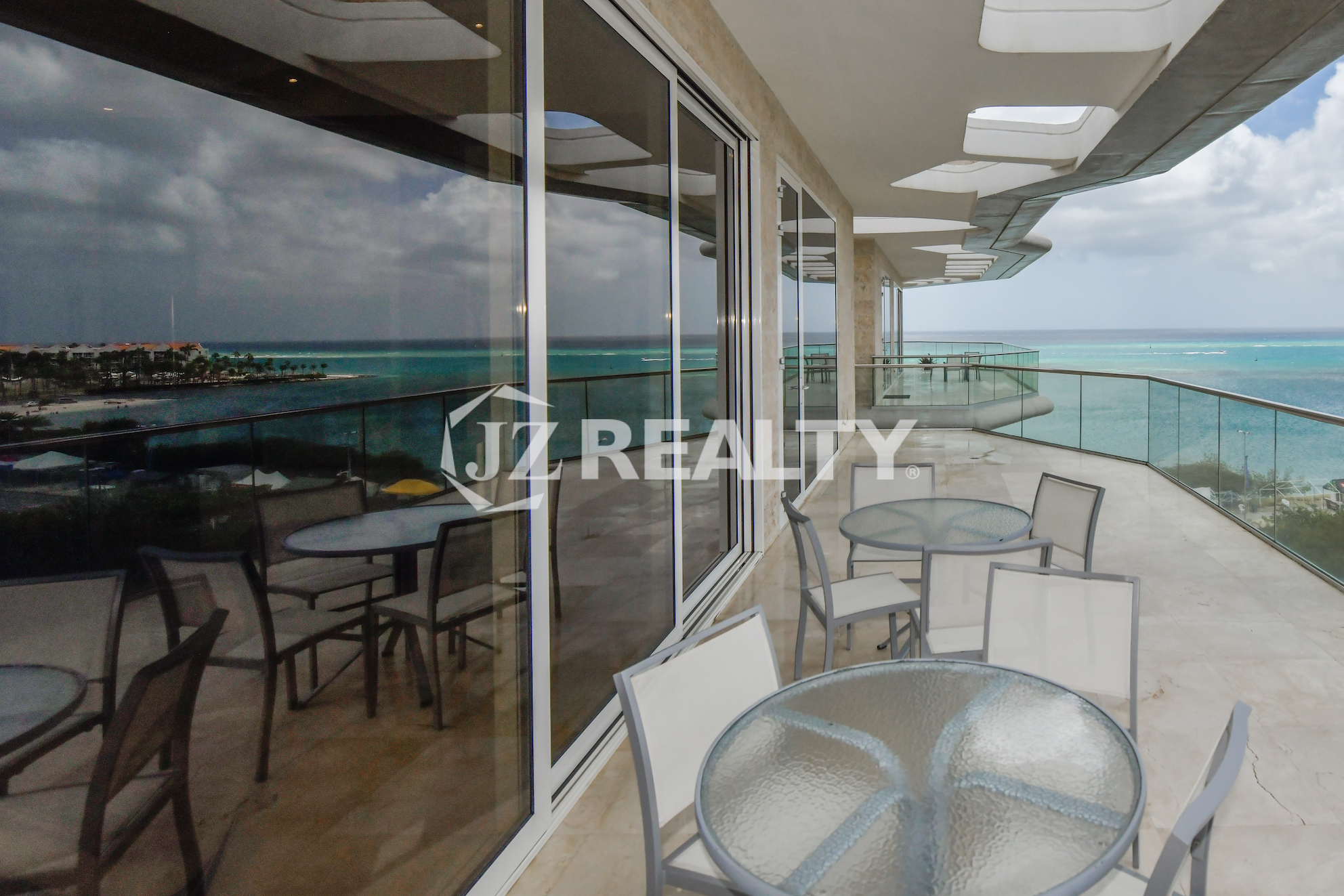 Spectacular oceanfront balcony at Coral Shell Penthouse B, offering ample seating, glass railings, and uninterrupted sea views.
