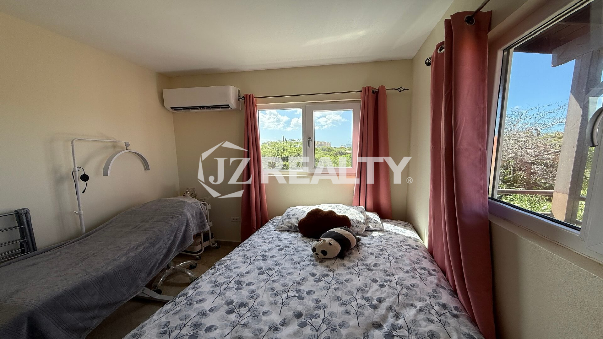 Bright guest bedroom with three windows, pink curtains, and nature views at Alto Vista 26-W Apartment 8.