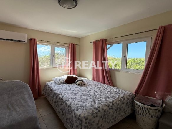 Guest bedroom with two beds, pink curtains, and garden view at Alto Vista 26-W Apartment 8.