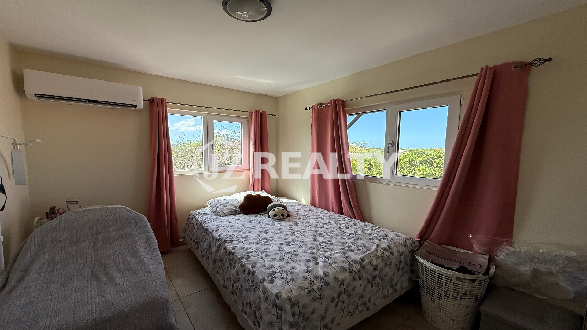 Guest bedroom with two beds, pink curtains, and garden view at Alto Vista 26-W Apartment 8.