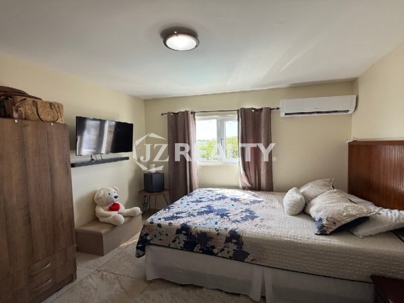 Master bedroom with wardrobe, TV, and window overlooking greenery in Alto Vista 26-W Apartment 8.