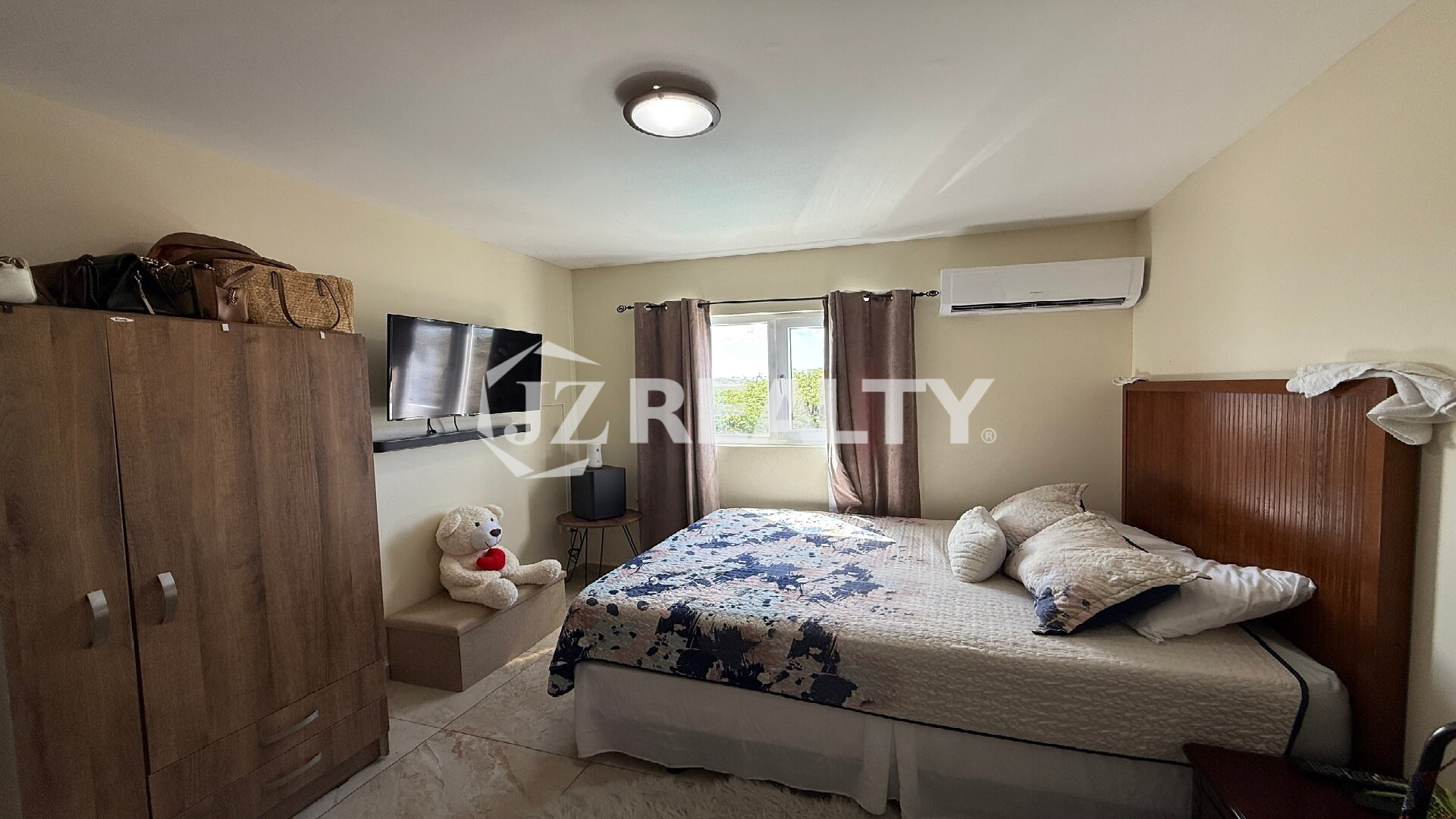 Master bedroom with wardrobe, TV, and window overlooking greenery in Alto Vista 26-W Apartment 8.