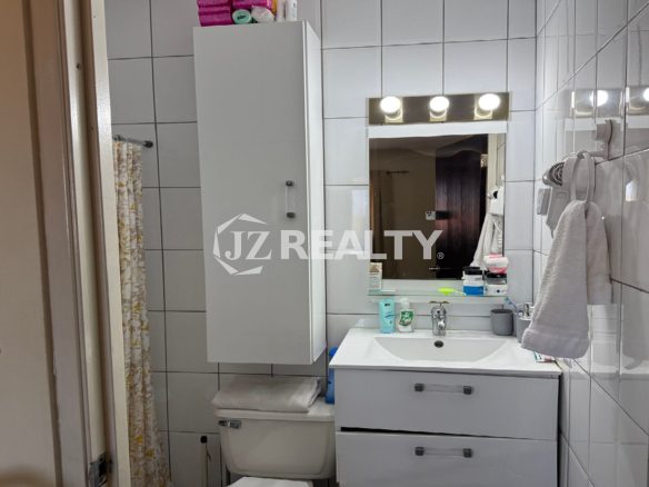 Bathroom vanity area with sink, mirror, and white cabinet.