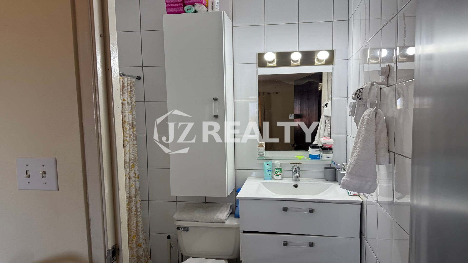 Bathroom vanity area with sink, mirror, and white cabinet.