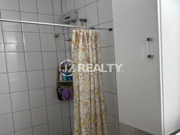 Tiled shower area with shower curtain and wall-mounted water heater.