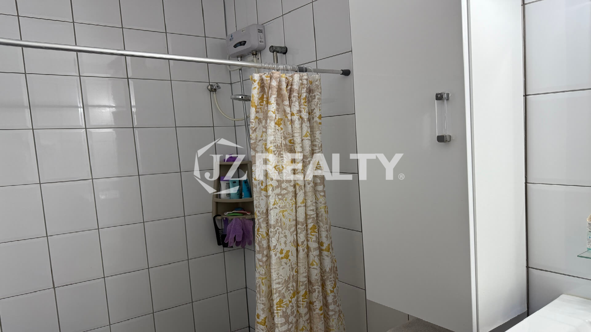Tiled shower area with shower curtain and wall-mounted water heater.