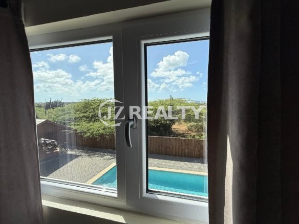 Window view of the swimming pool and natural greenery at Alto Vista 26-W Apartment 8.