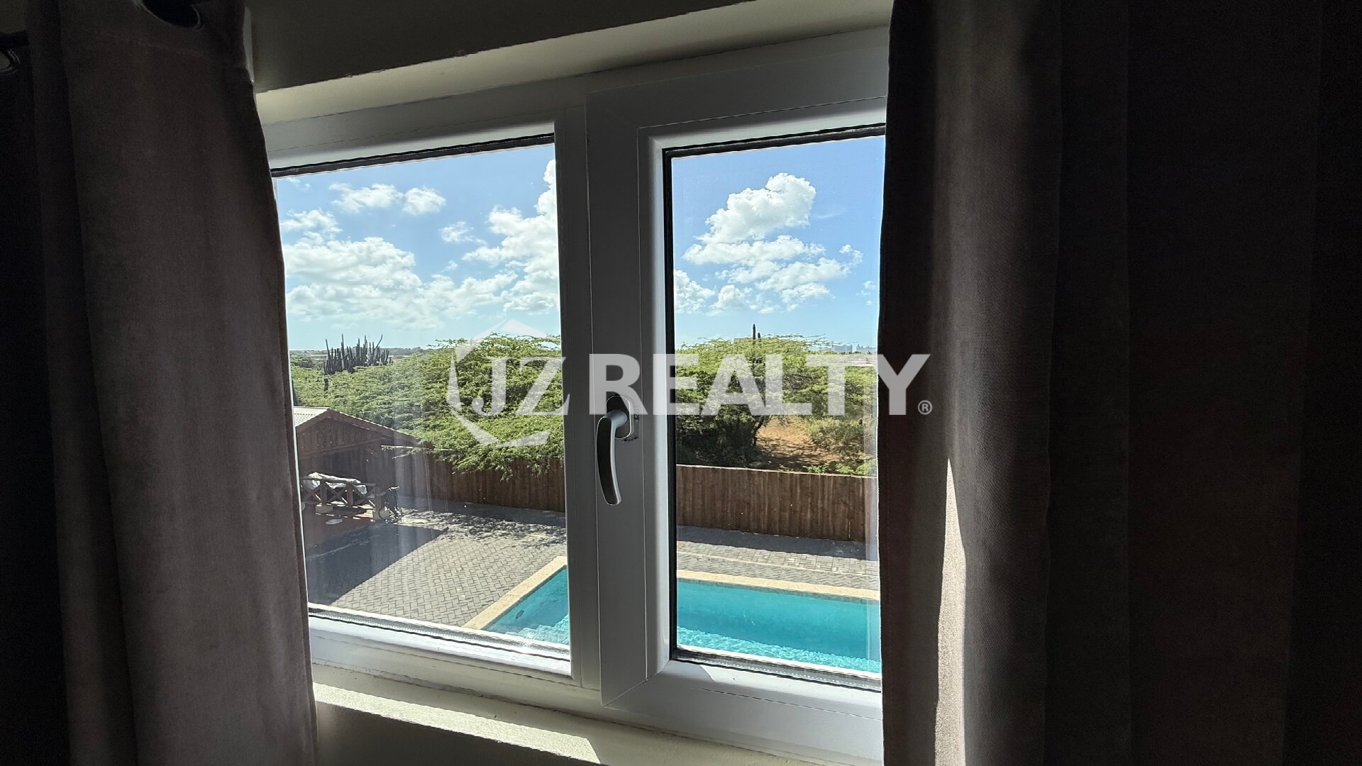 Window view of the swimming pool and natural greenery at Alto Vista 26-W Apartment 8.