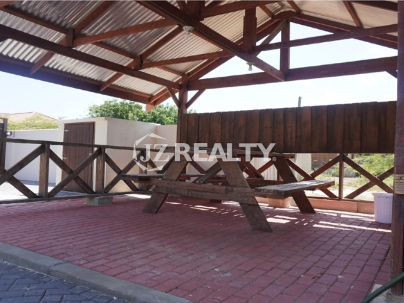 Covered wooden gazebo with picnic table on brick paving.