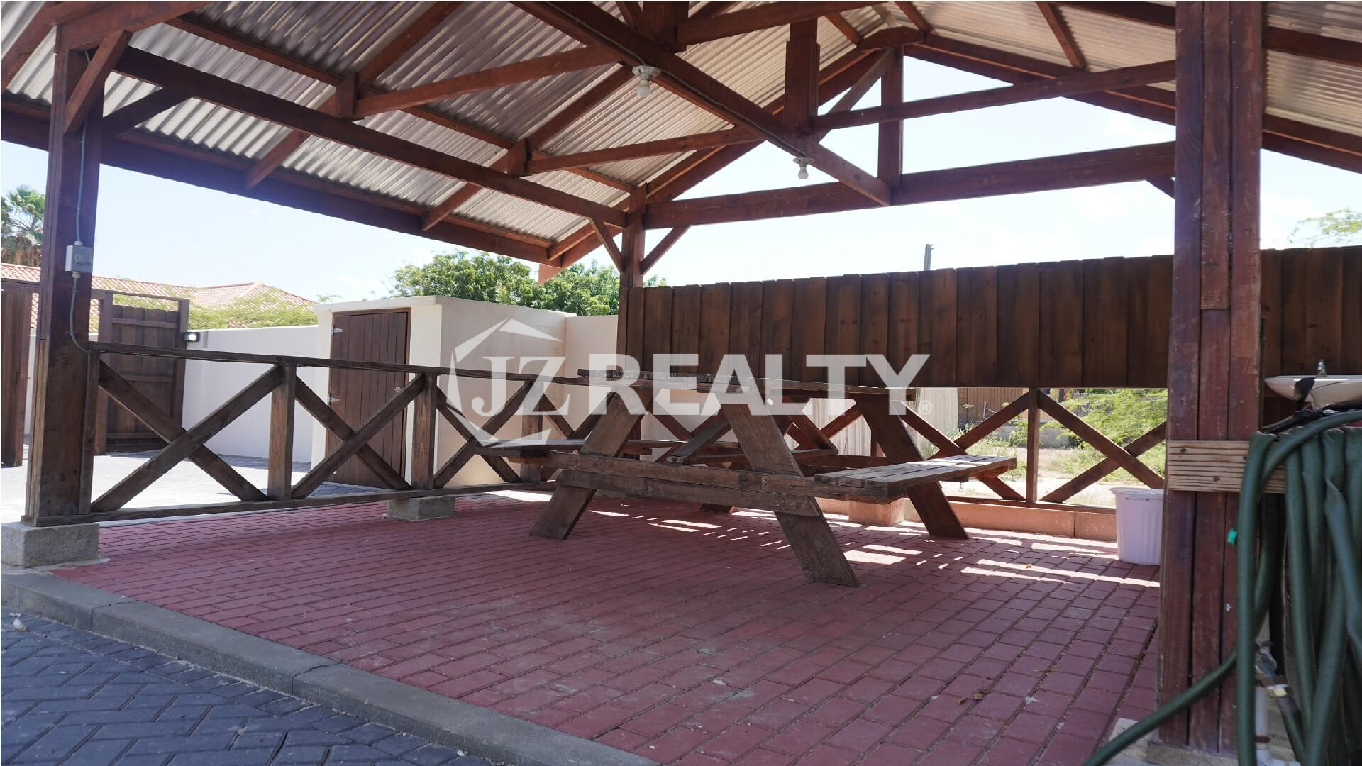 Covered wooden gazebo with picnic table on brick paving.