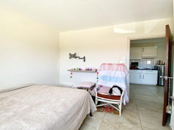 Small neutral bedroom showing doorway into kitchen and living area.