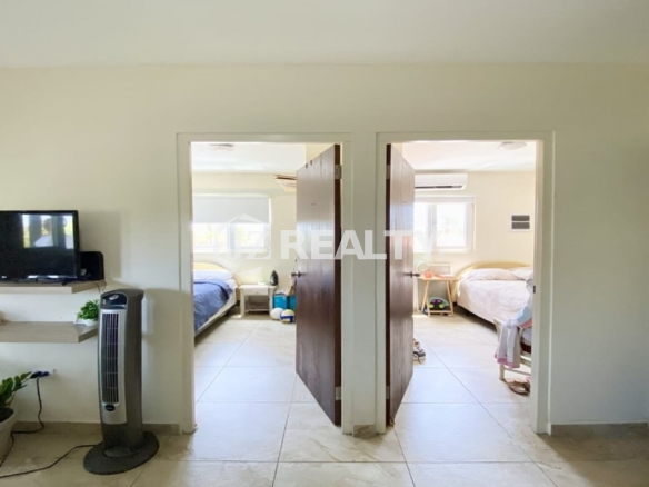 Shared hallway showing two open bedroom doors and wall-mounted TV in living area.