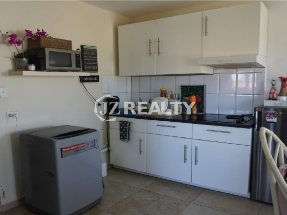 Compact kitchen with white cabinets, black countertop and washing machine.