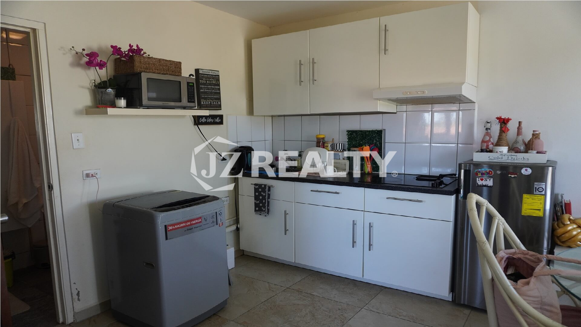 Compact kitchen with white cabinets, black countertop and washing machine.
