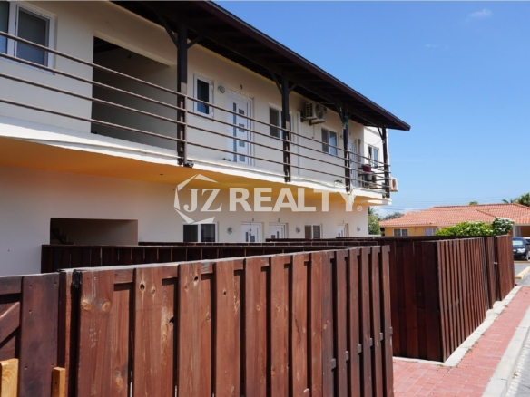 Two-story apartment building with wooden fenced patios and upper balcony.