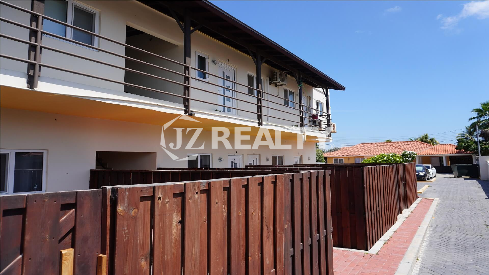 Two-story apartment building with wooden fenced patios and upper balcony.