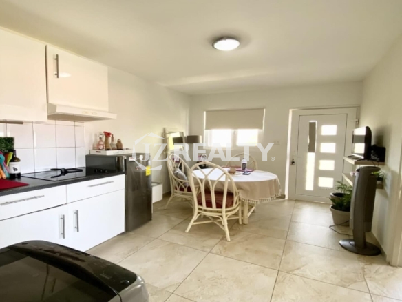 Open kitchen and dining area with round table, chairs and window light.