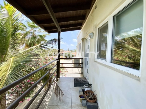 Second-floor balcony with metal railings and tropical palm view.