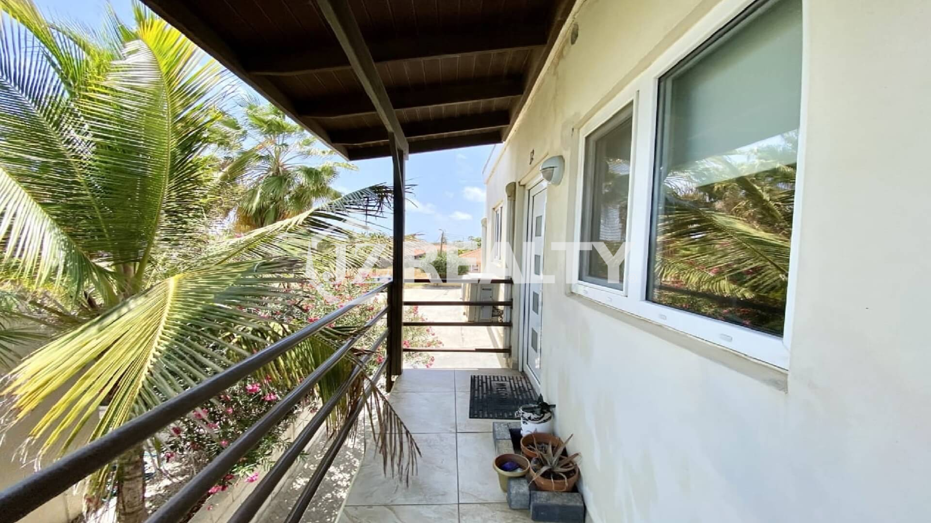 Second-floor balcony with metal railings and tropical palm view.
