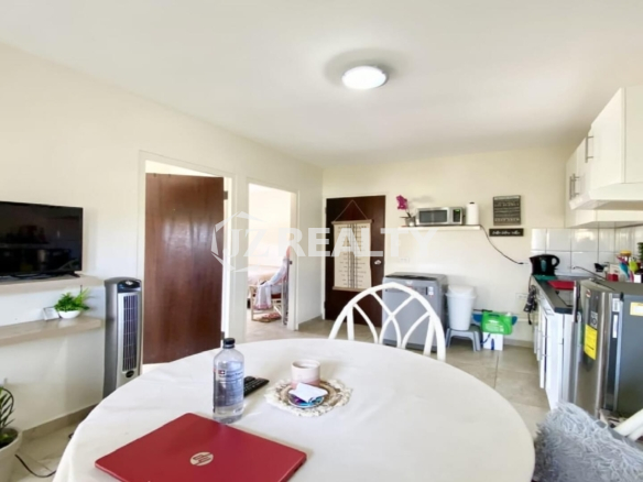 Round dining table positioned near open doorways to bedrooms and kitchen.
