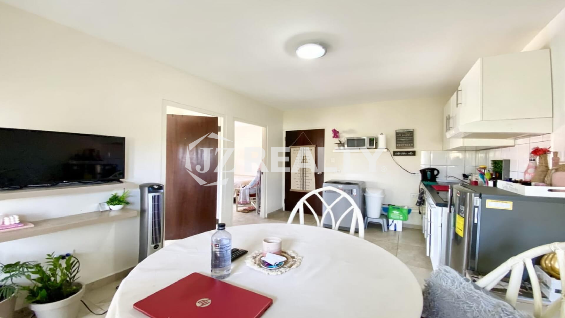 Round dining table positioned near open doorways to bedrooms and kitchen.