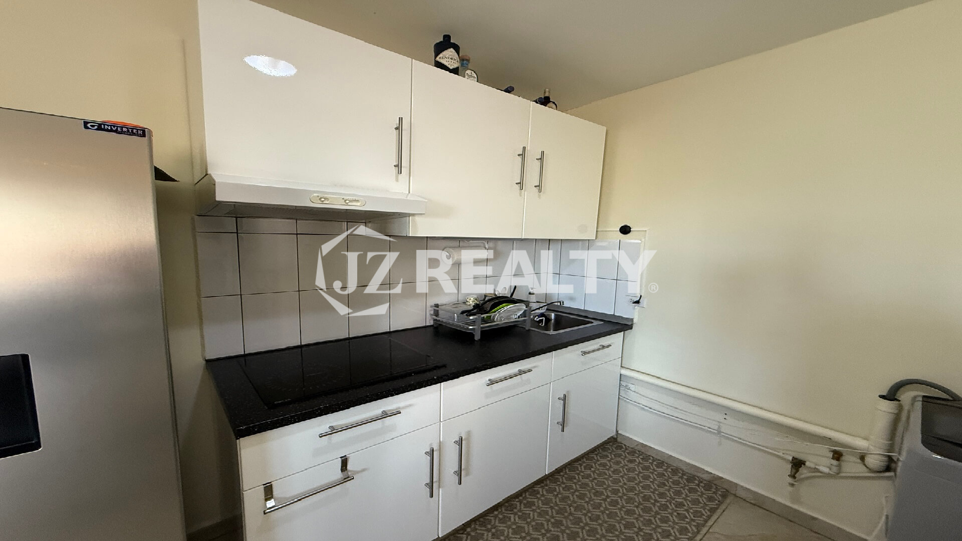 Close-up of the kitchen cabinetry, countertop, stovetop, and tiled backsplash.