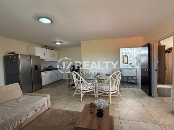Kitchen area featuring stove, cabinets, fridge, and doorway to a tiled bathroom.