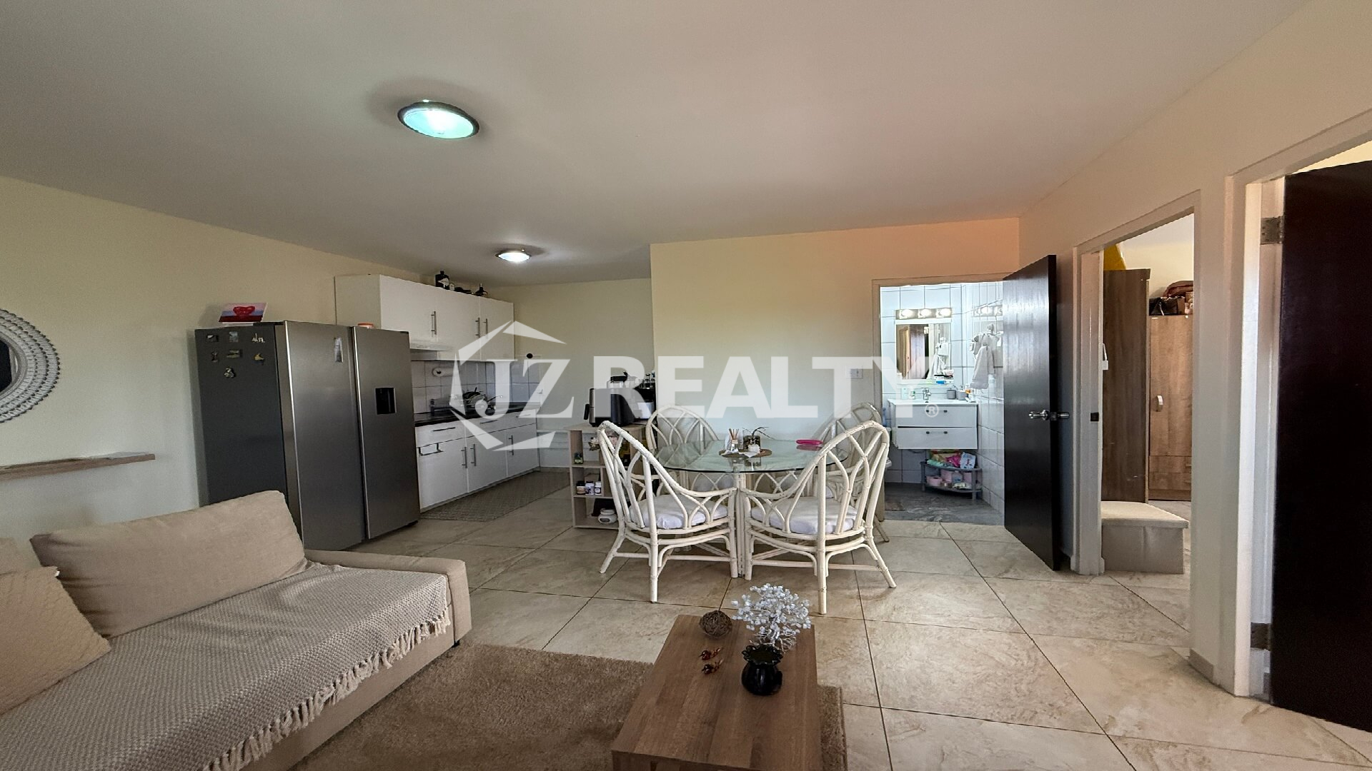 Kitchen area featuring stove, cabinets, fridge, and doorway to a tiled bathroom.
