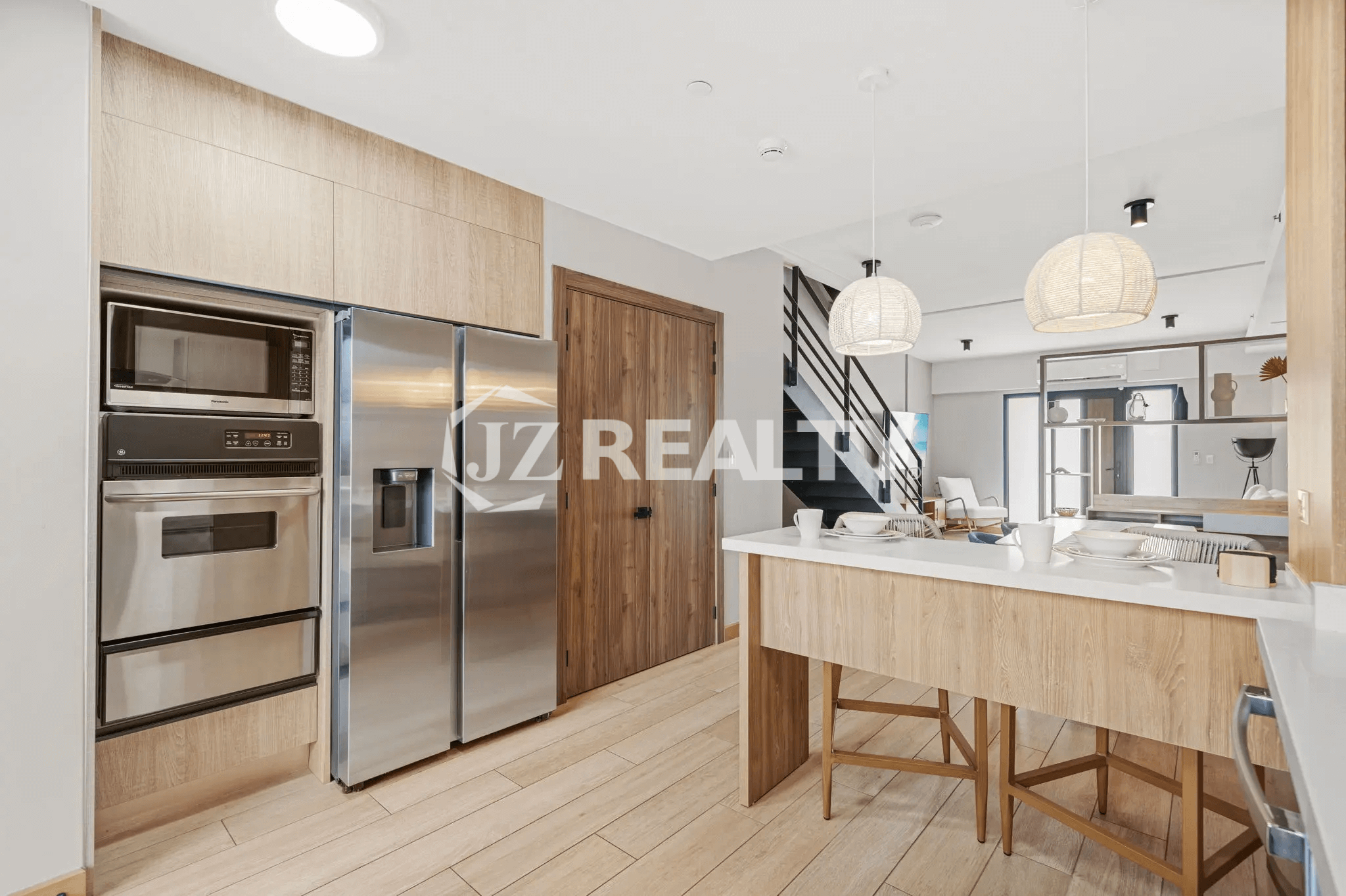 View of the stainless steel refrigerator, built-in microwave, and oven within the modern kitchen of Porta al Sole Unit 10.