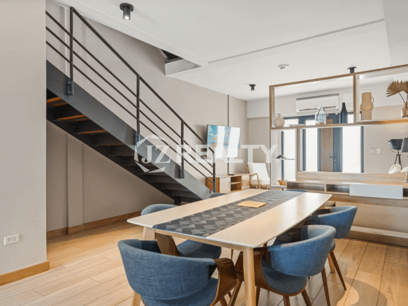 Dining area in Porta al Sole Unit 10 featuring a table with blue chairs and a modern, exposed metal and wood staircase leading upstairs.