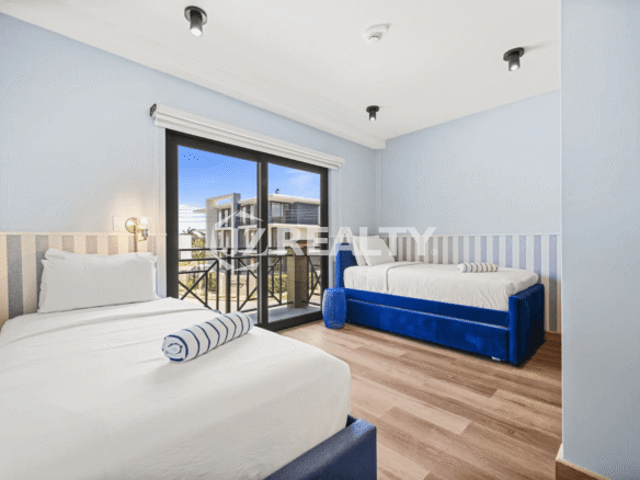 Guest bedroom in Porta al Sole Unit 10 with two twin beds featuring blue accents, a sliding glass door to a balcony, and light blue walls.