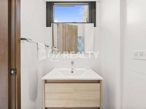 Compact half bath in Porta al Sole Unit 10 featuring a modern vanity, mirror, and white tiled walls.