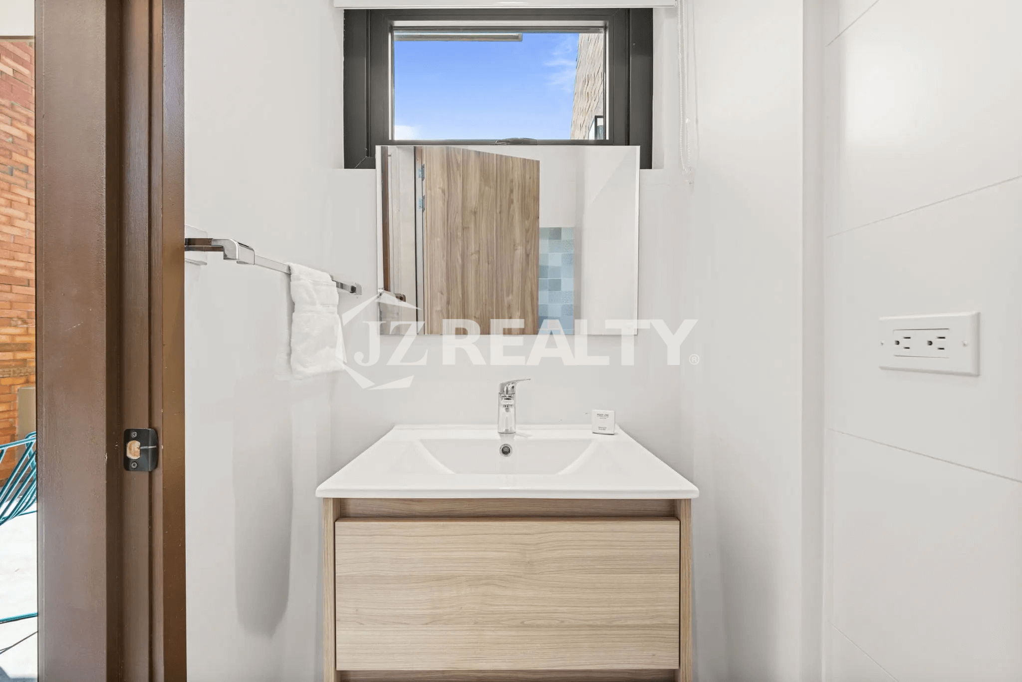 Compact half bath in Porta al Sole Unit 10 featuring a modern vanity, mirror, and white tiled walls.