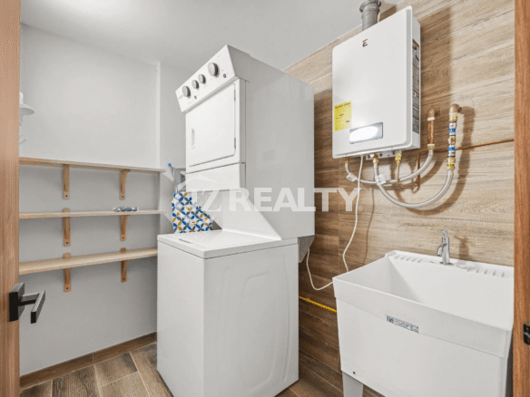 Laundry room in Porta al Sole Unit 10 featuring a stacked washer and dryer, utility sink, water heater, and storage shelves.