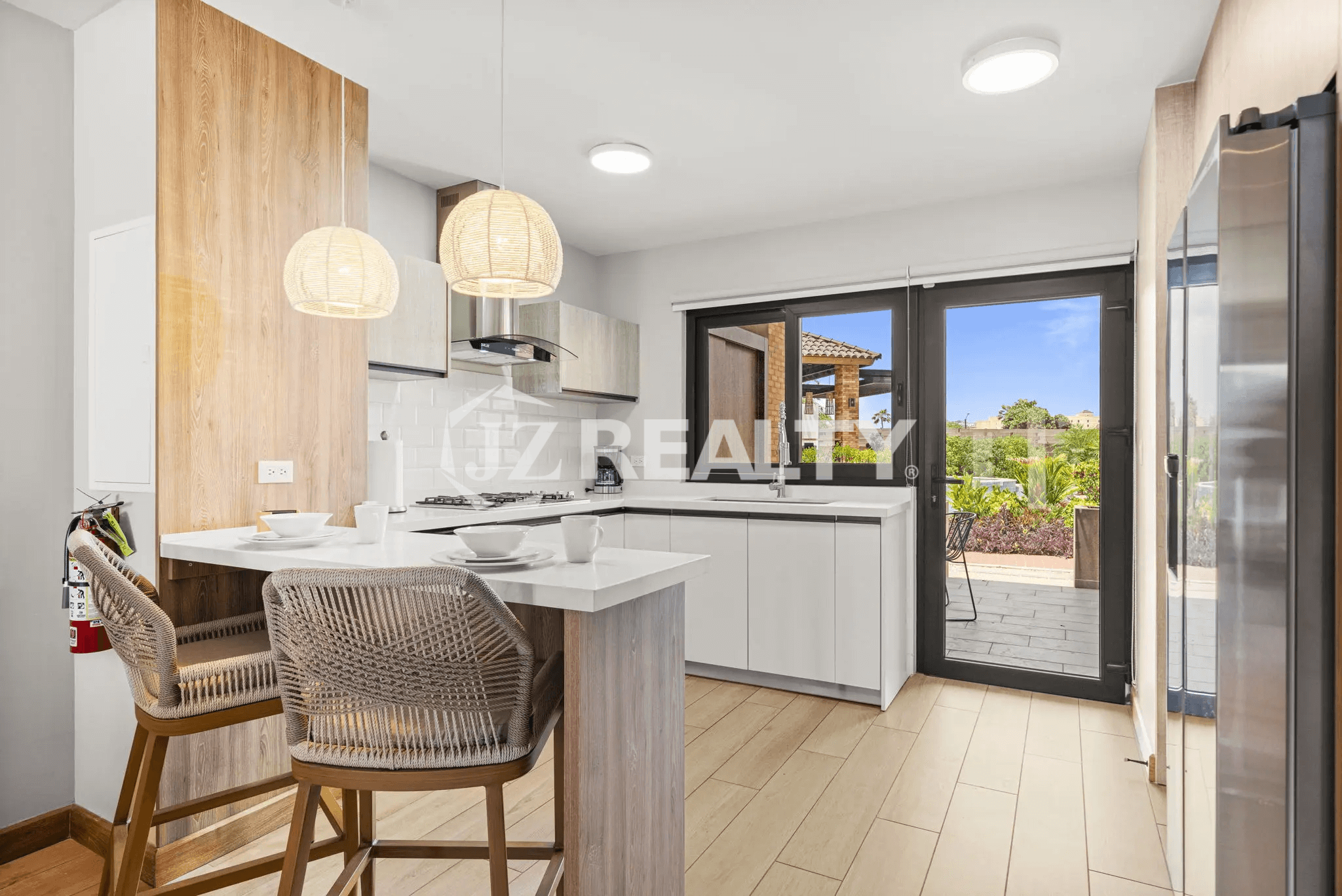 Bright, modern kitchen in Porta al Sole Unit 10 with white countertops, rattan pendant lights, and breakfast bar seating.