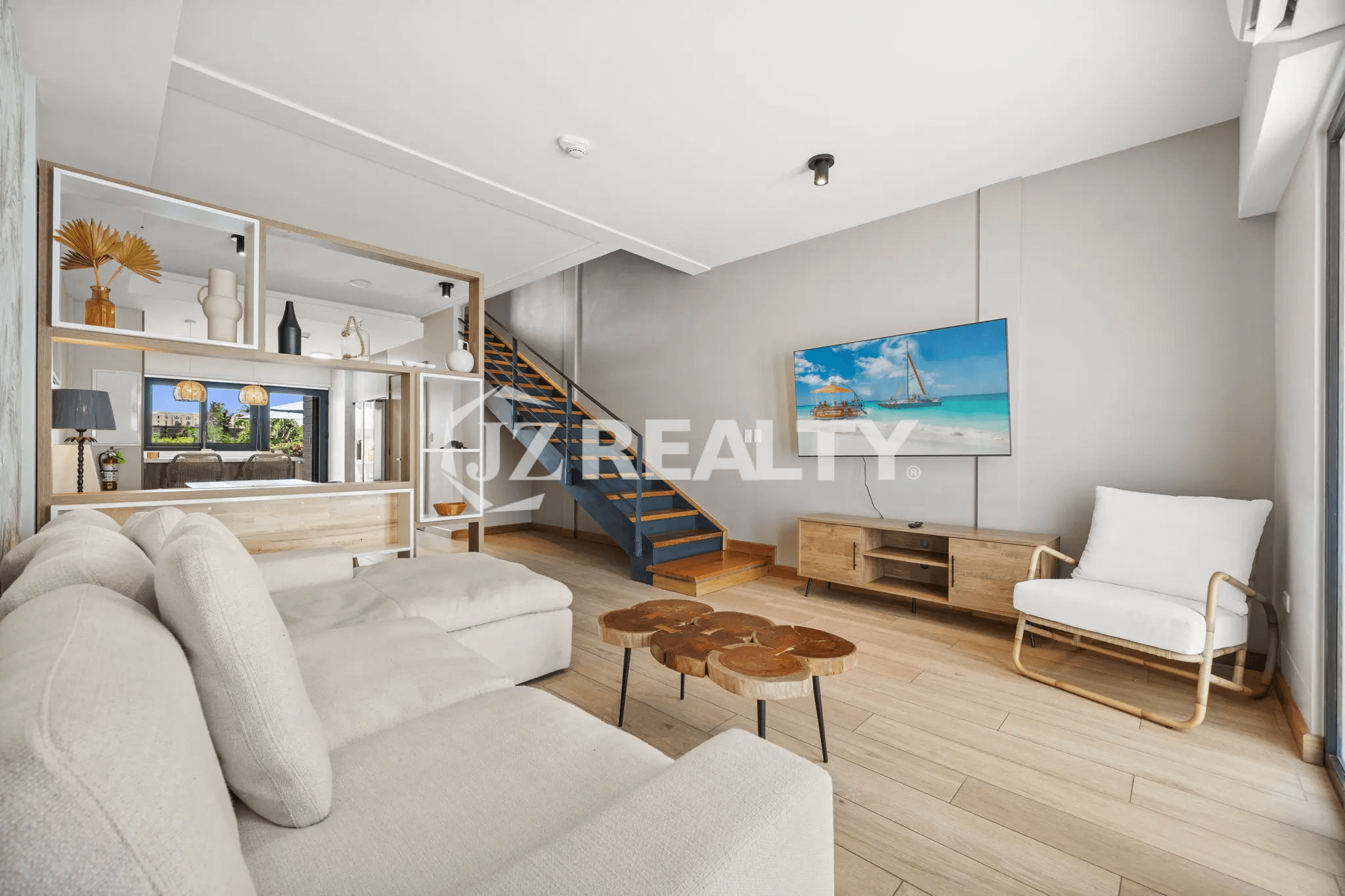 Wide view of the contemporary living room in Porta al Sole Unit 10 with a large sectional sofa, wood coffee table, and an open staircase.