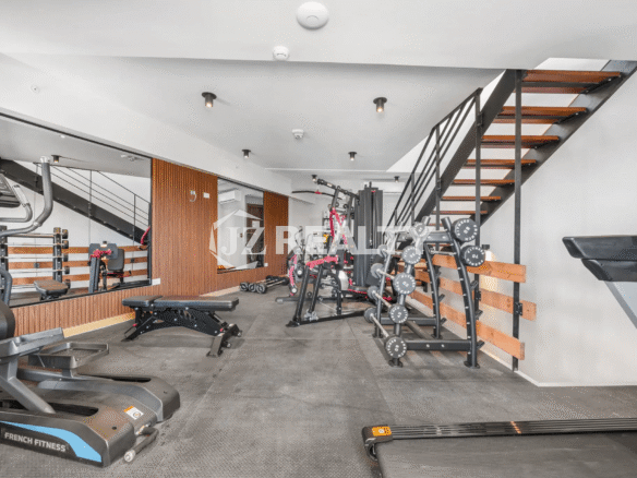 Interior of the community gym at Porta al Sole, equipped with cardio machines, free weights, and strength training equipment.