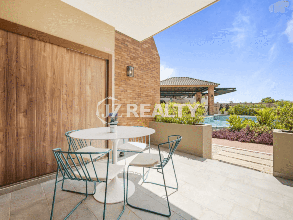 Outdoor patio space at Porta al Sole Unit 10 with a small dining set, overlooking the communal pool area and landscaping.