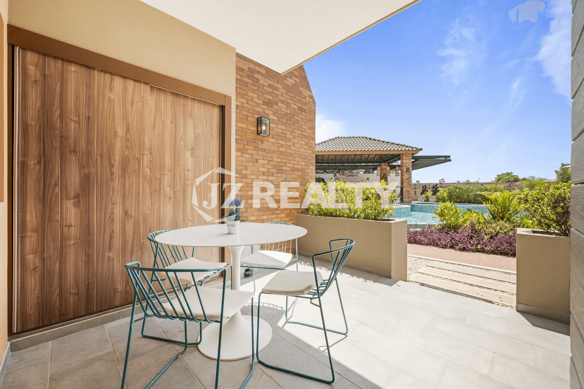 Outdoor patio space at Porta al Sole Unit 10 with a small dining set, overlooking the communal pool area and landscaping.