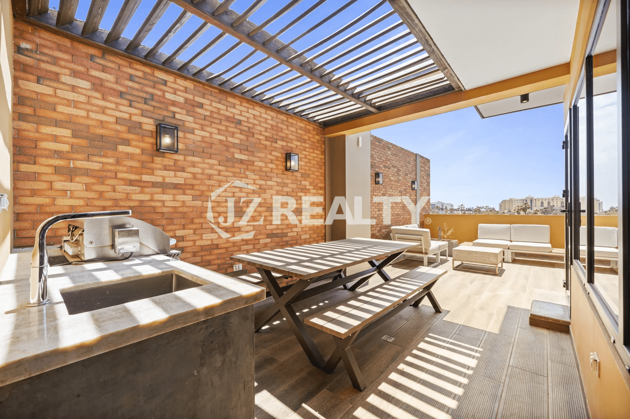 Rooftop terrace at Porta al Sole Unit 10 with a shaded pergola, brick wall, outdoor dining table, built-in BBQ/sink area, and lounge seating.