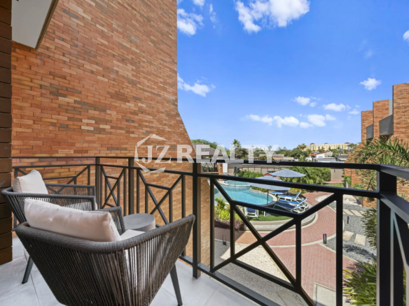 Porta al Sole Unit 11 private balcony with modern woven chairs, overlooking the resort pool and surrounding complex.