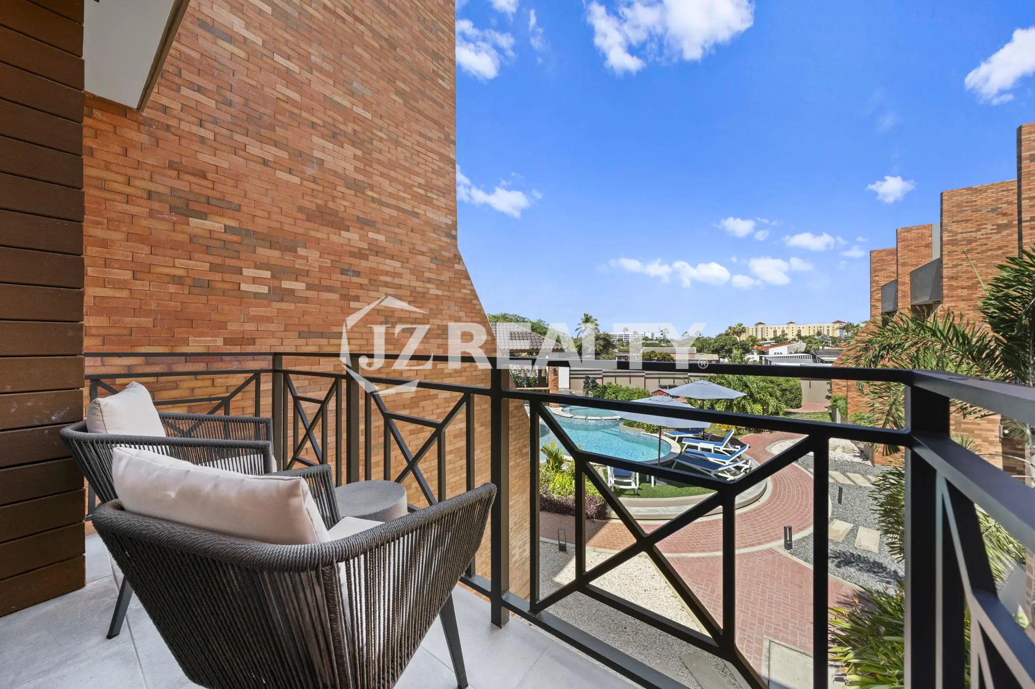 Porta al Sole Unit 11 private balcony with modern woven chairs, overlooking the resort pool and surrounding complex.