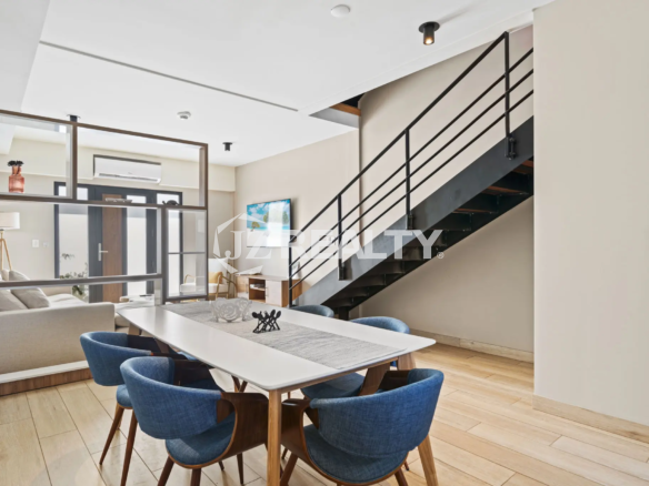 Porta al Sole Unit 11 open-plan dining area with a long white table, modern blue chairs, and a contemporary open-riser staircase with black metal railings.